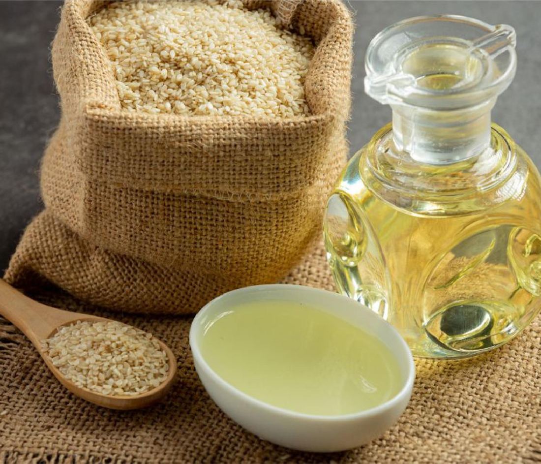 Saco de ajonjolí, cuchara con semillas y aceite de ajonjolí en una jarra de vidrio